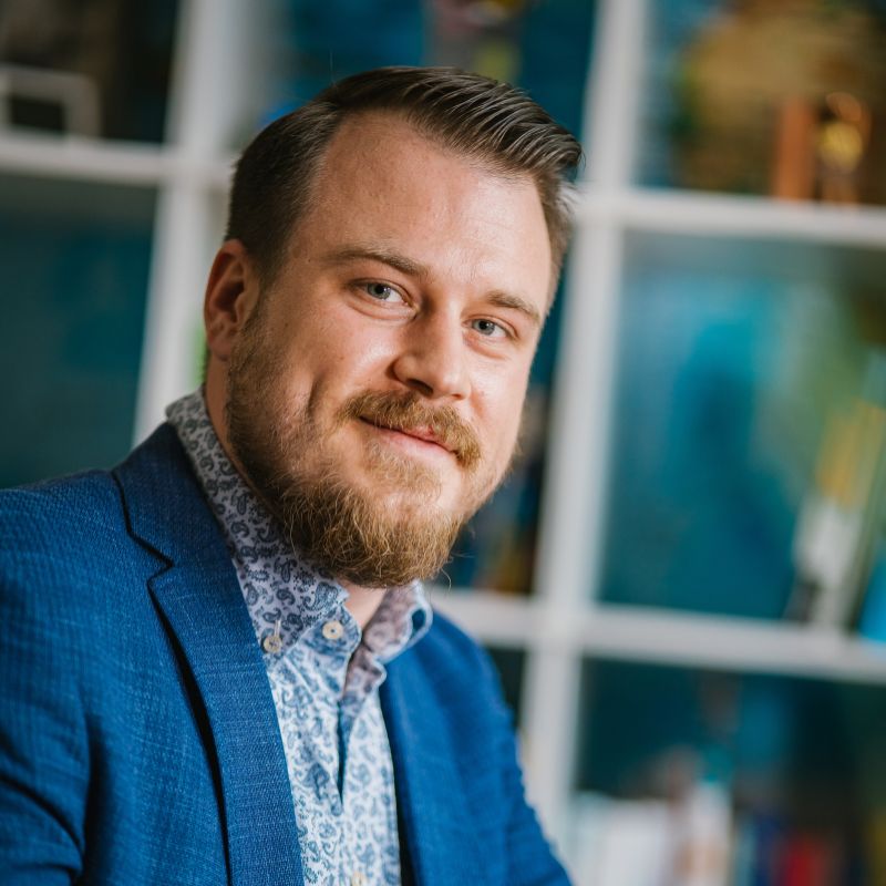 Mann mit Bart trägt einen blauen Anzug und ein gemustertes Hemd, schaut in die Kamera. | Mave Consulting